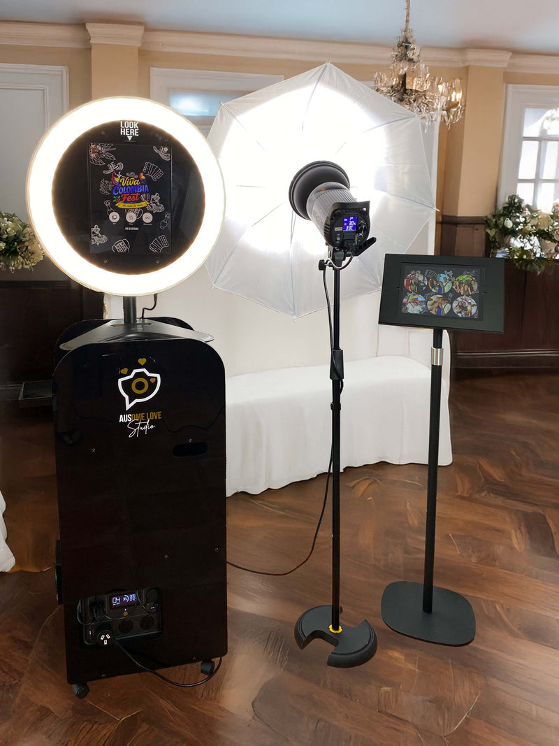 An Ausome Love Studio photo booth set up in an elegant venue, with a ring light, professional umbrella lighting and a print display stand, ready for take-home prints
