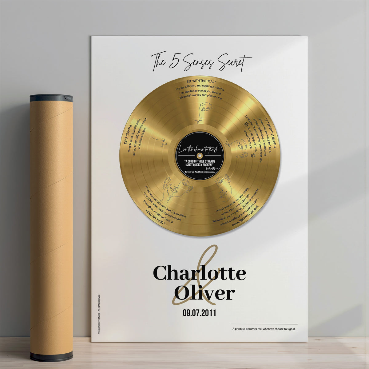 Unframed personalised couple print with a gold vinyl record on a cream background, featuring five sense-themed love messages and line-art faces, the names Charlotte & Oliver and the date 09.07.2011 below, standing beside a kraft cardboard posting tube.