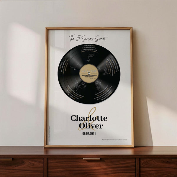 Personalised vinyl record poster with five love modules, couple names Charlotte and Oliver, framed in oak on a timber sideboard