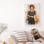 Custom vintage photo restoration watercolor wall art by Ausome Love Studio, featuring a colorized woman's portrait on canvas hanging above a sofa, with the original black and white photo shown on a smartphone for comparison.