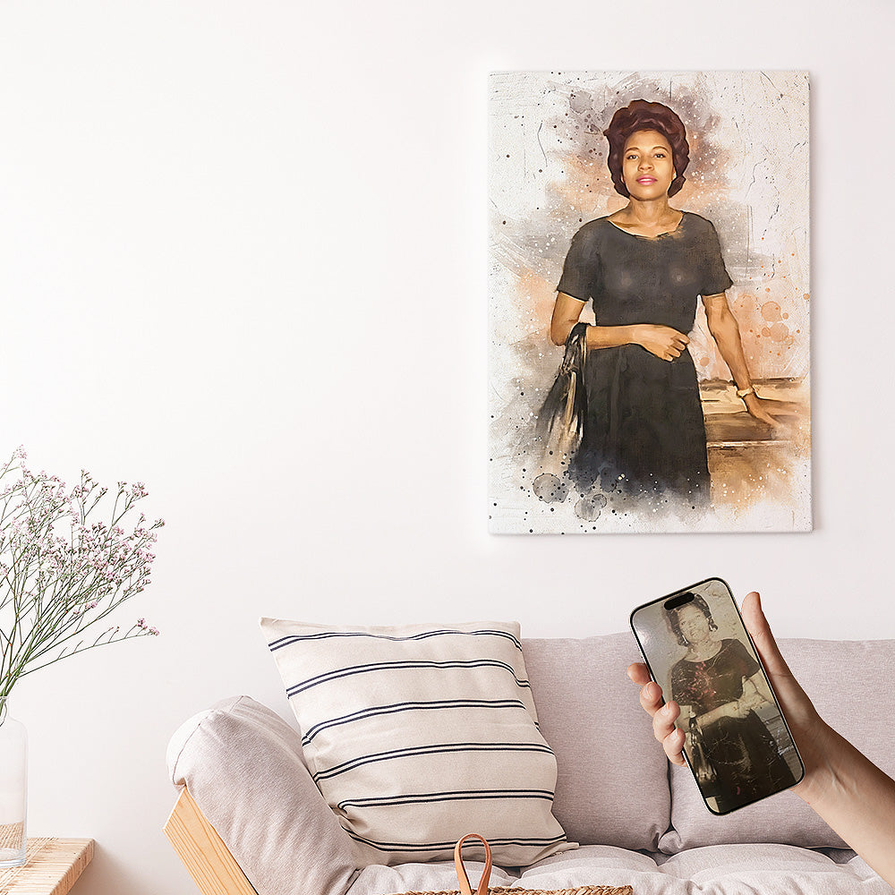 Custom vintage photo restoration watercolor wall art by Ausome Love Studio, featuring a colorized woman's portrait on canvas hanging above a sofa, with the original black and white photo shown on a smartphone for comparison.