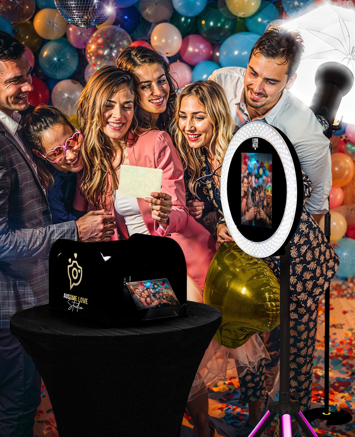 A group of friends laughing together at an Ausome Love Studio selfie photo booth, with a ring light and colourful balloon backdrop, at an intimate celebration