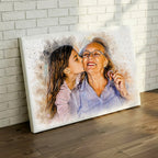 Heartwarming watercolor portrait of a granddaughter kissing her grandmother, displayed as a large gallery-wrapped canvas leaning against a white brick wall by Ausome Love Studio.